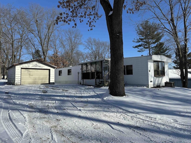 view of front of home with a garage, a sunroom, and an outbuilding