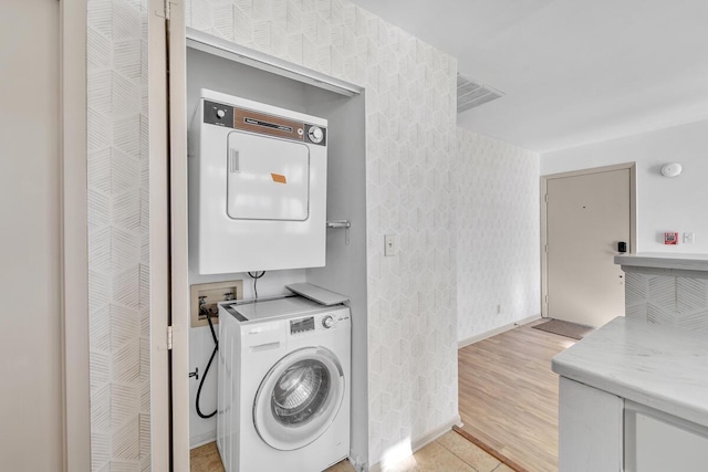 washroom with stacked washer and clothes dryer and light hardwood / wood-style floors