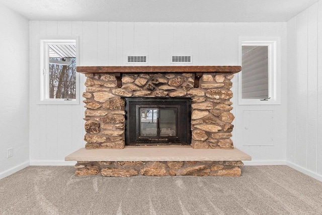 interior details featuring baseboards, visible vents, carpet, and a stone fireplace