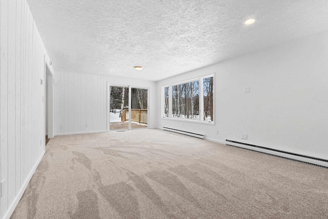 empty room with a baseboard heating unit, a textured ceiling, and light colored carpet