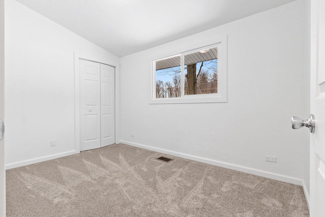 unfurnished bedroom with visible vents, baseboards, vaulted ceiling, a closet, and carpet floors