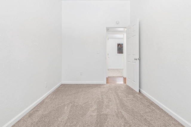 carpeted empty room featuring baseboards