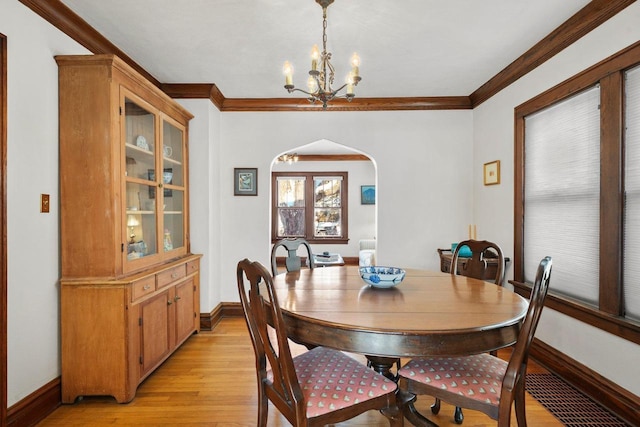 dining area featuring light wood-type flooring, crown molding, and an inviting chandelier