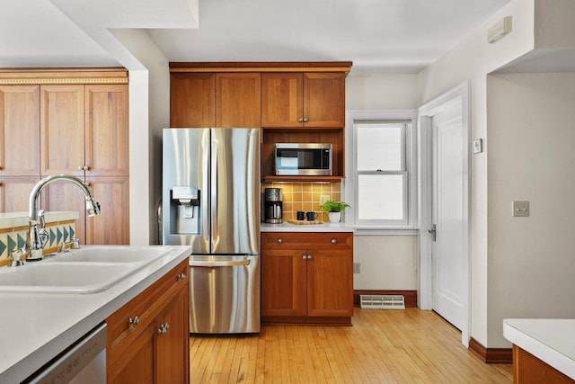 kitchen featuring sink, appliances with stainless steel finishes, tasteful backsplash, and light hardwood / wood-style floors