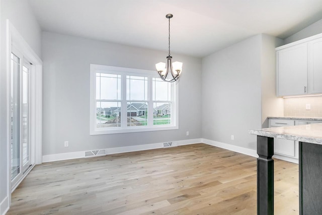 unfurnished dining area with a notable chandelier and light hardwood / wood-style floors