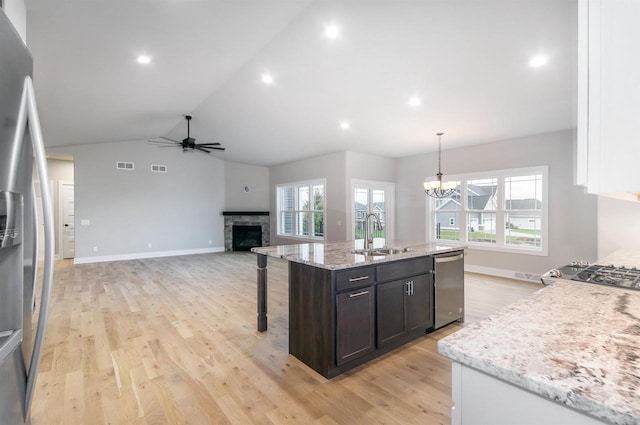 kitchen featuring pendant lighting, sink, a kitchen island with sink, stainless steel appliances, and light stone countertops