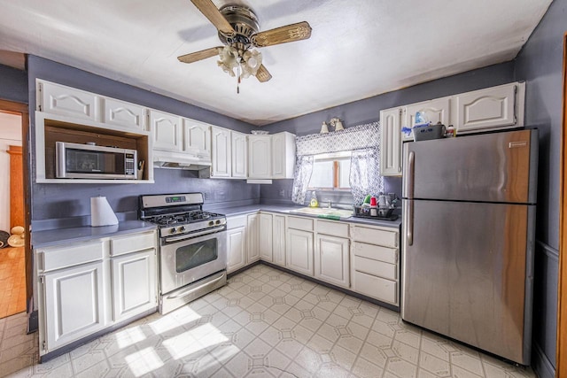 kitchen with light floors, appliances with stainless steel finishes, white cabinetry, a sink, and under cabinet range hood