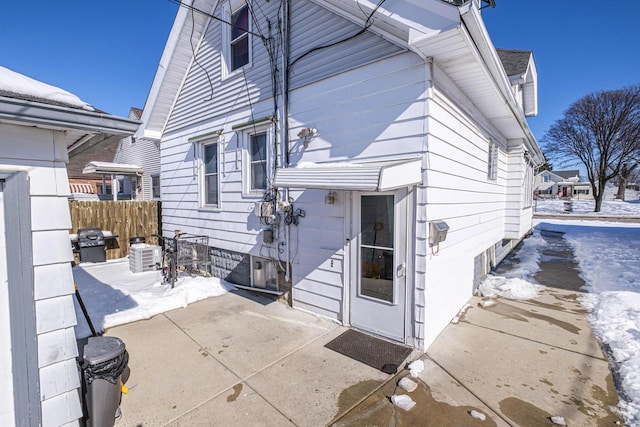 snow covered rear of property with a patio area and fence