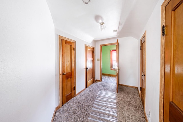 hallway with baseboards and light colored carpet