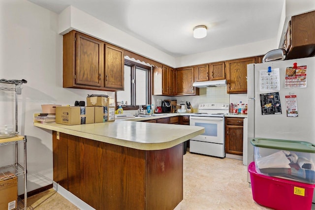 kitchen with backsplash, white appliances, and kitchen peninsula