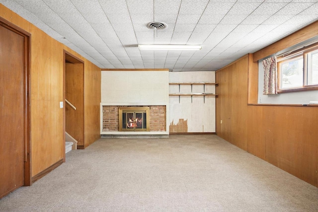 basement with a brick fireplace, wood walls, and light colored carpet