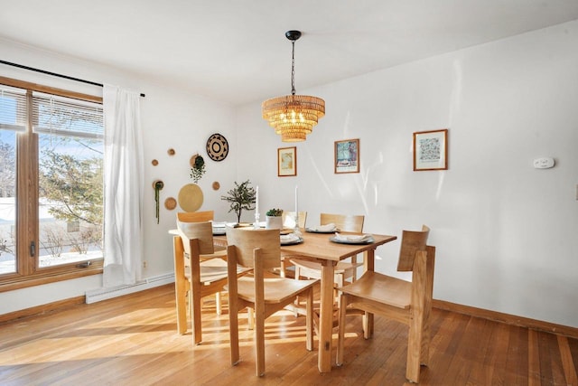 dining area featuring baseboard heating, hardwood / wood-style flooring, and a notable chandelier