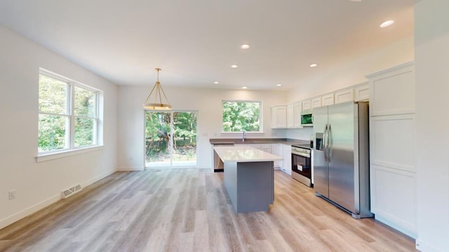 kitchen with decorative light fixtures, sink, white cabinets, a center island, and stainless steel appliances