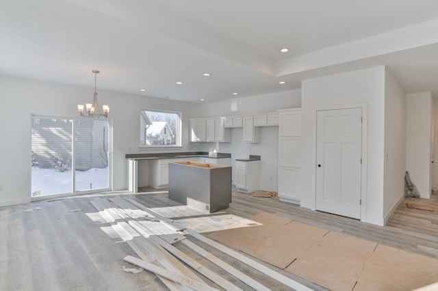 kitchen featuring an inviting chandelier, a kitchen island, pendant lighting, light hardwood / wood-style floors, and white cabinets