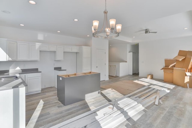 kitchen featuring ceiling fan, white cabinetry, light hardwood / wood-style floors, a kitchen island, and decorative light fixtures