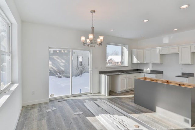 kitchen with hanging light fixtures, a notable chandelier, white cabinets, and light wood-type flooring