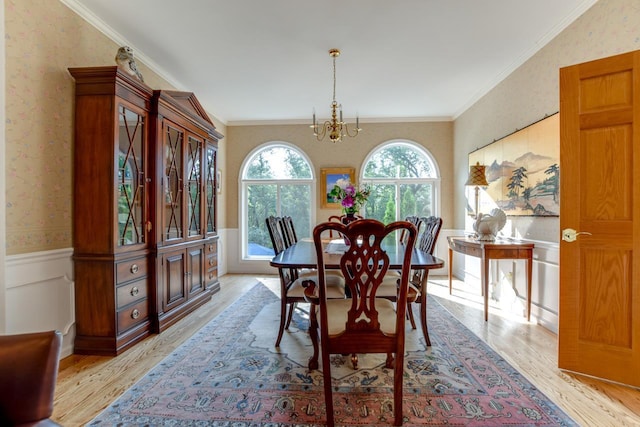 dining area with crown molding, an inviting chandelier, and light hardwood / wood-style flooring