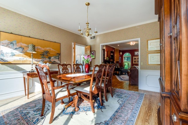 dining area featuring crown molding, wood-type flooring, and a notable chandelier