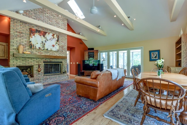 living room with a brick fireplace, light hardwood / wood-style flooring, high vaulted ceiling, and beamed ceiling