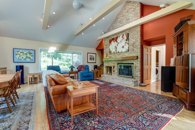 living room with high vaulted ceiling, a fireplace, washer / dryer, and light hardwood / wood-style floors