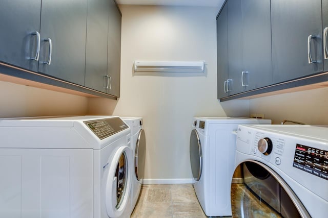 clothes washing area with cabinets and separate washer and dryer