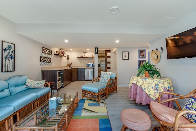 living room with beverage cooler, indoor wet bar, and light hardwood / wood-style flooring