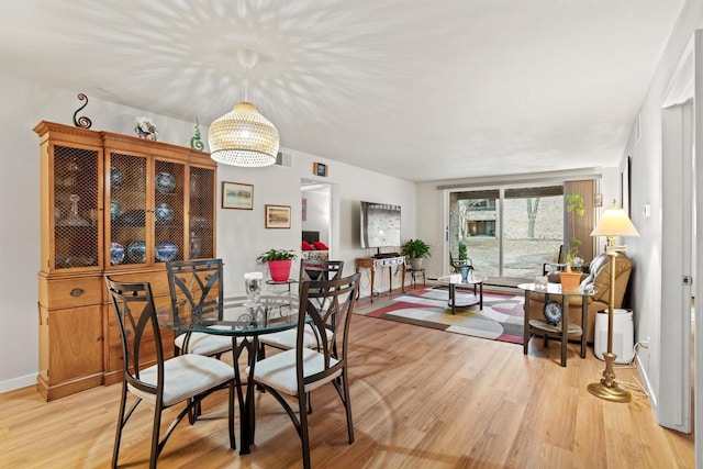 dining space with light wood finished floors, visible vents, baseboards, and a notable chandelier