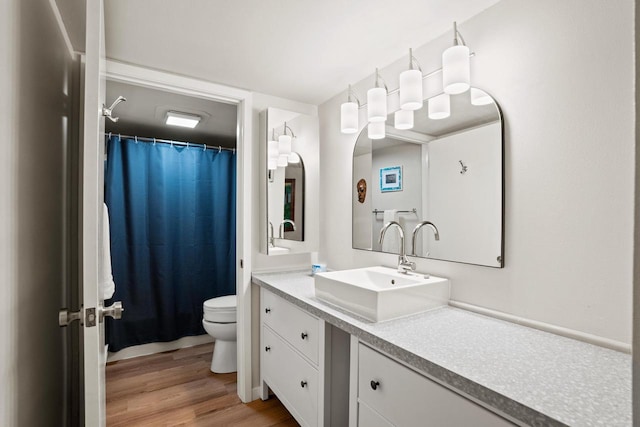 full bath with toilet, a shower with curtain, wood finished floors, and vanity