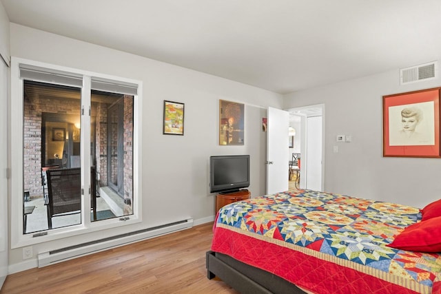 bedroom featuring baseboards, a baseboard radiator, visible vents, and wood finished floors