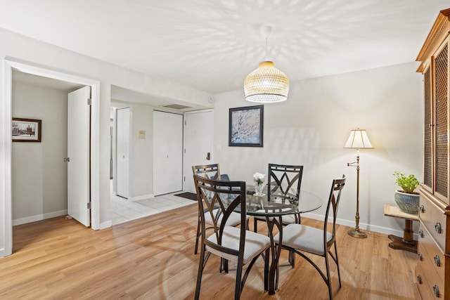 dining room with a chandelier, light wood-style flooring, and baseboards