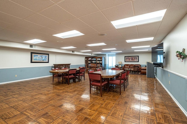 dining room featuring visible vents, a drop ceiling, and baseboards