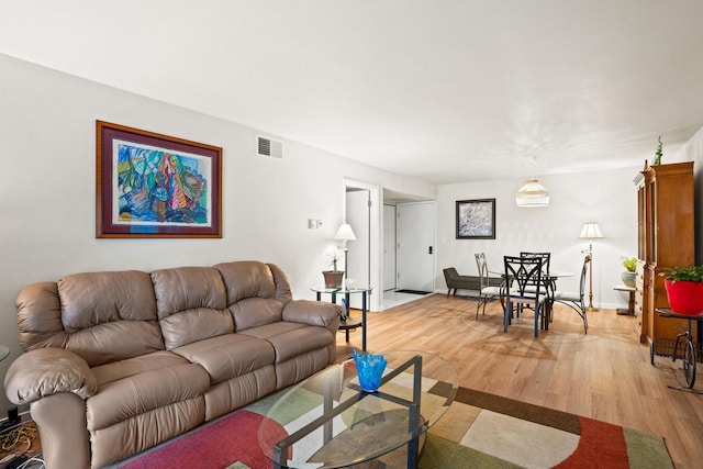 living area featuring visible vents, light wood-style flooring, and baseboards