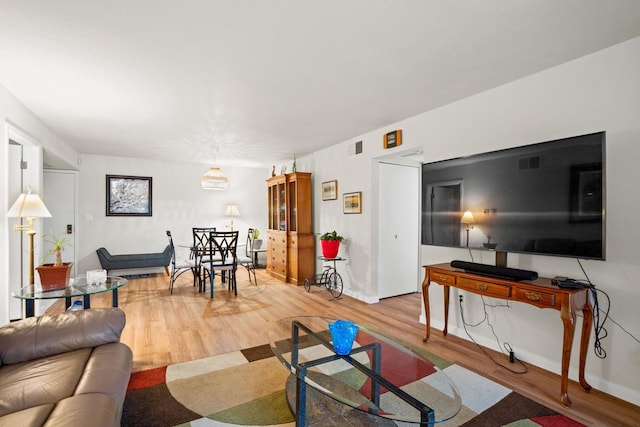 living room with visible vents, baseboards, and wood finished floors