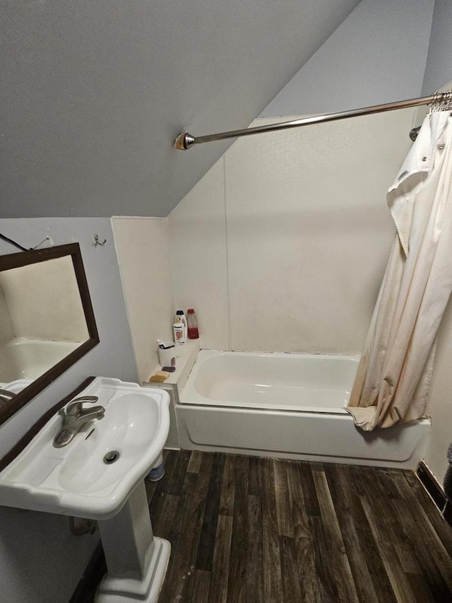 bathroom featuring hardwood / wood-style flooring, lofted ceiling, and shower / bathtub combination with curtain