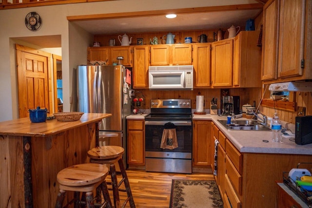 kitchen with sink, a breakfast bar area, stainless steel appliances, and light wood-type flooring