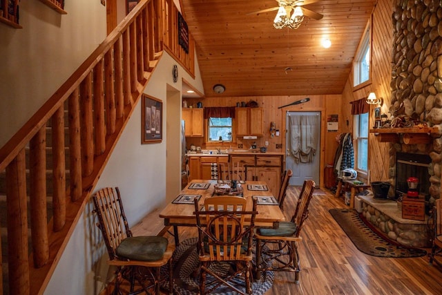 dining area with high vaulted ceiling, a fireplace, wood-type flooring, ceiling fan, and wood ceiling