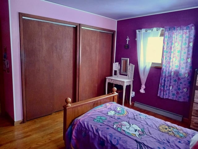 bedroom featuring wood finished floors, multiple closets, and baseboard heating