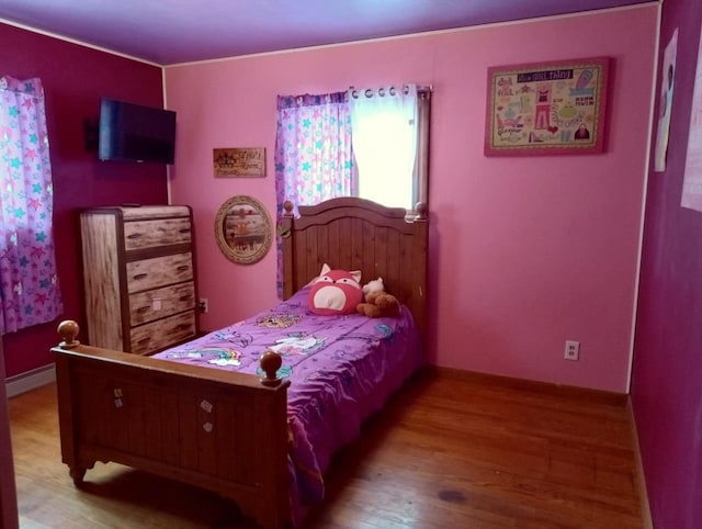 bedroom with a baseboard heating unit and wood finished floors