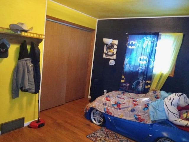 bedroom featuring wood finished floors, visible vents, and a closet