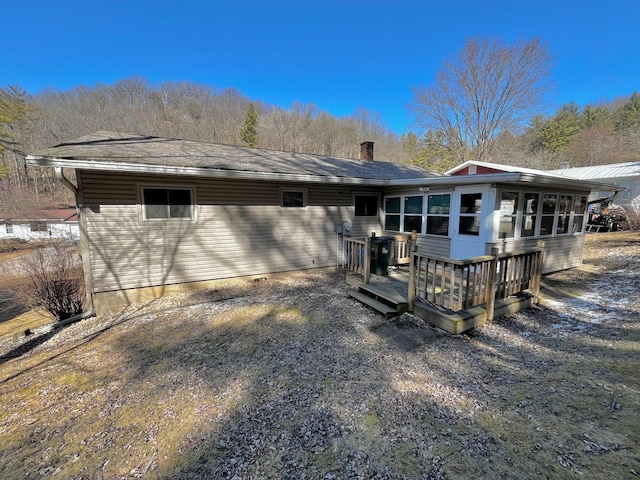 back of property featuring a deck, a sunroom, and a shingled roof