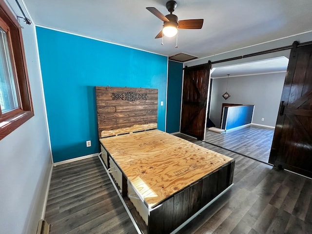 bedroom with dark wood-style floors, baseboards, a barn door, and a ceiling fan