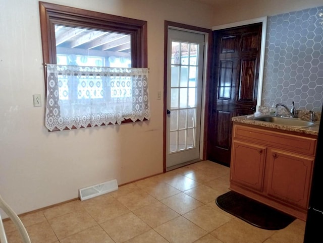 entryway featuring a sink, visible vents, baseboards, and light tile patterned floors