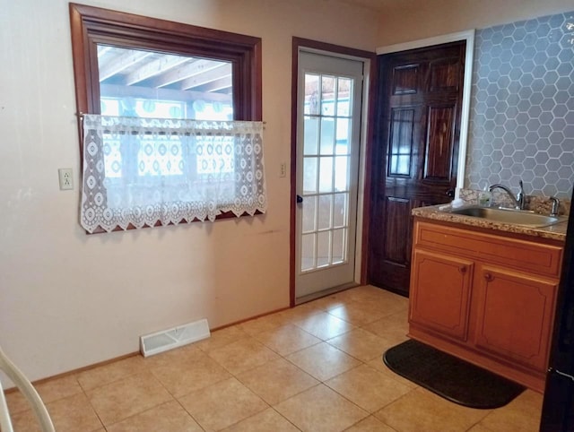 entryway featuring a sink, visible vents, baseboards, and light tile patterned floors