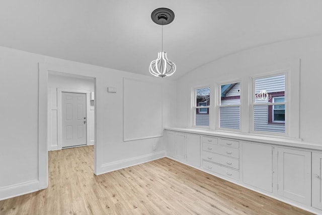 unfurnished dining area featuring vaulted ceiling and light wood-type flooring