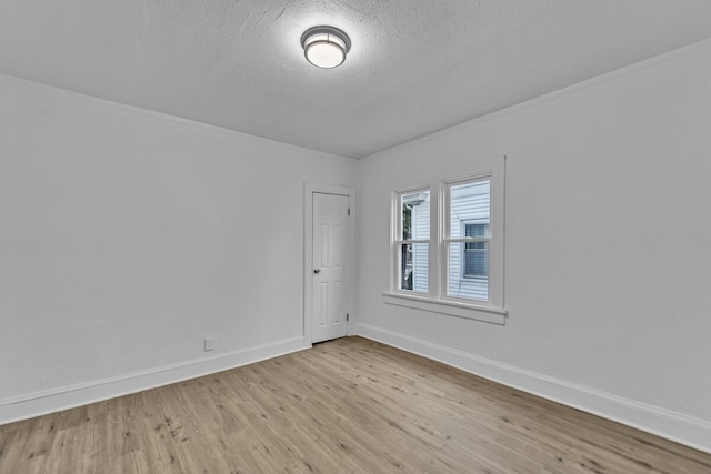 empty room with a textured ceiling and light hardwood / wood-style flooring