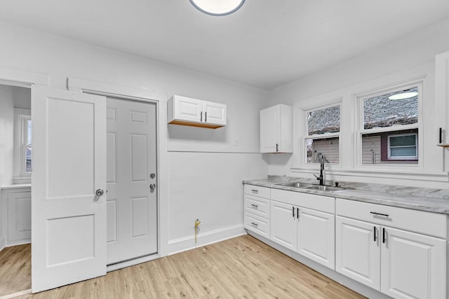 kitchen with white cabinetry, light hardwood / wood-style floors, and sink