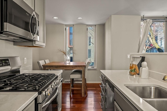 kitchen featuring dark wood finished floors, stainless steel appliances, light countertops, a sink, and recessed lighting