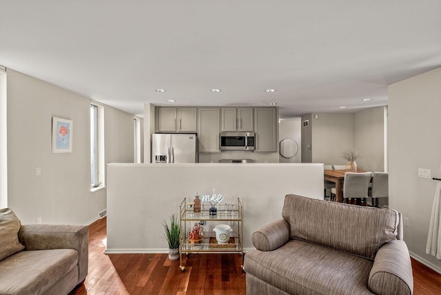 living area featuring baseboards, dark wood-type flooring, and recessed lighting