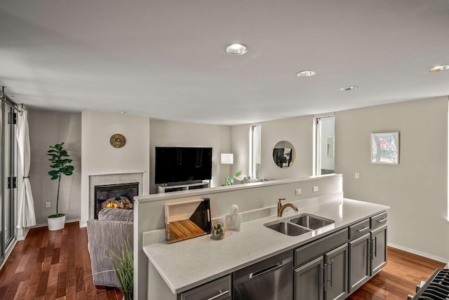 kitchen featuring dark wood-style floors, open floor plan, a sink, a tile fireplace, and dishwasher