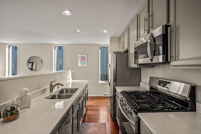 kitchen featuring dark wood finished floors, stainless steel appliances, light countertops, gray cabinetry, and a sink